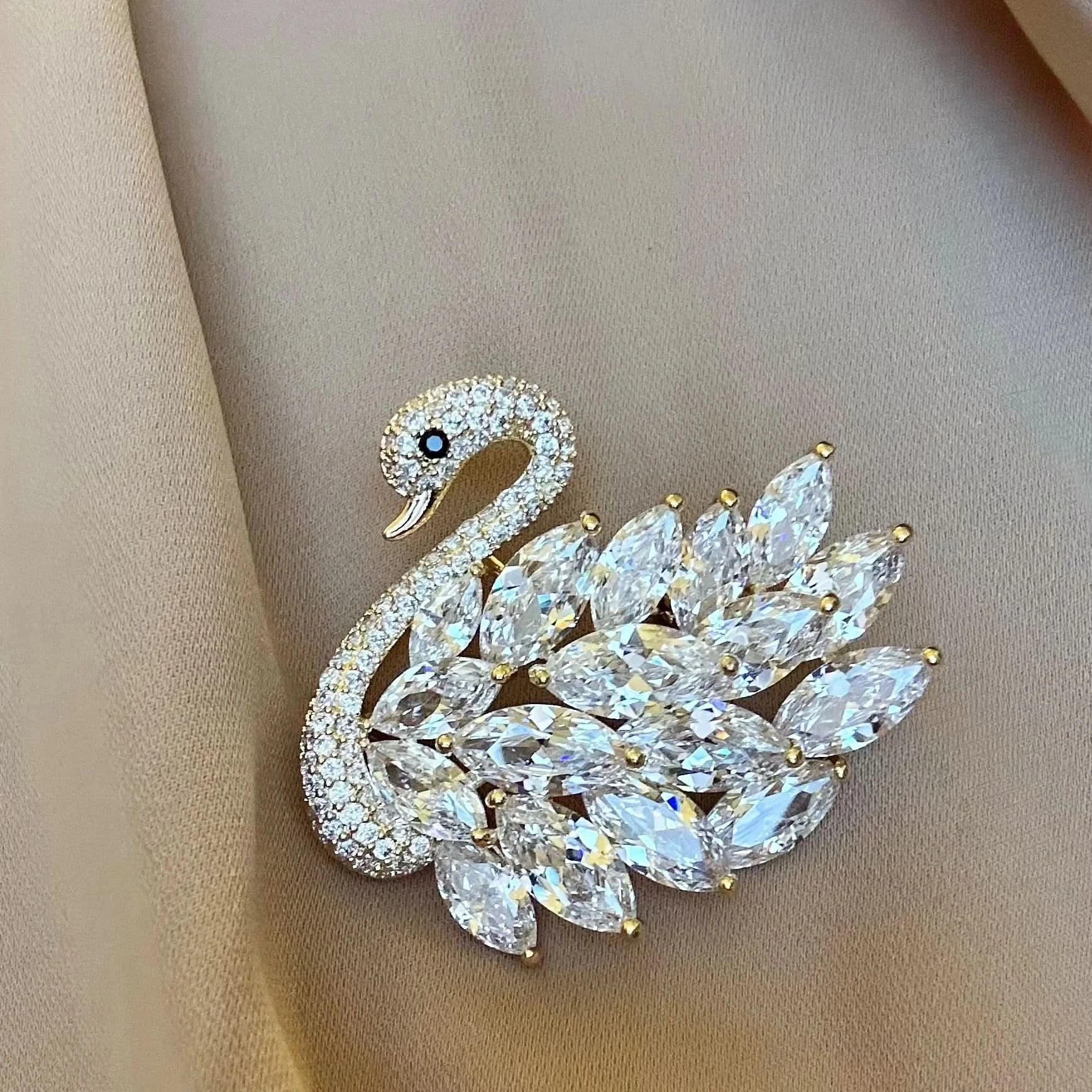 Elegant swan-shaped brooch with crystal details on a beige background