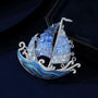 Close-up of graduated blue crystal sails and clear crystal wave details on a silver-tone sailing ship brooch