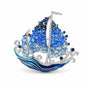 Blue crystal sailing ship brooch with silver-tone mast and enamel ocean waves on a white background