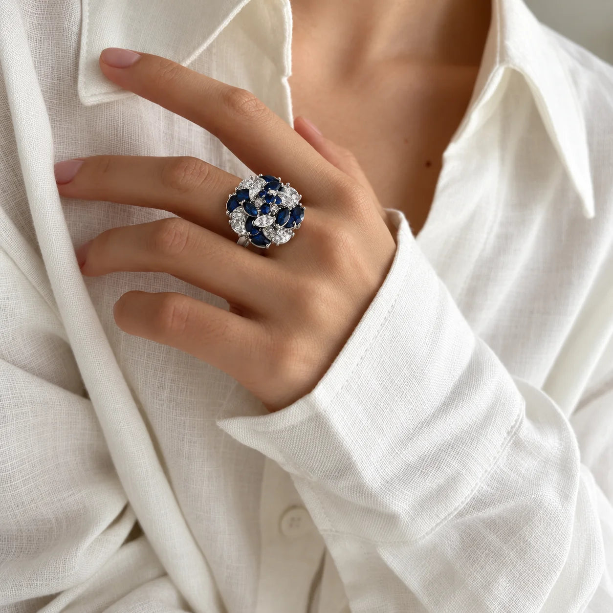 Woman wearing a blue and clear zirconia floral cluster statement ring