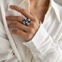 Woman wearing a blue and clear zirconia floral cluster statement ring