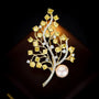 Close-up of yellow faceted crystals arranged along curved gold-tone branches with pearl accent