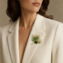 Green crystal maple leaf brooch worn on a cream blazer lapel