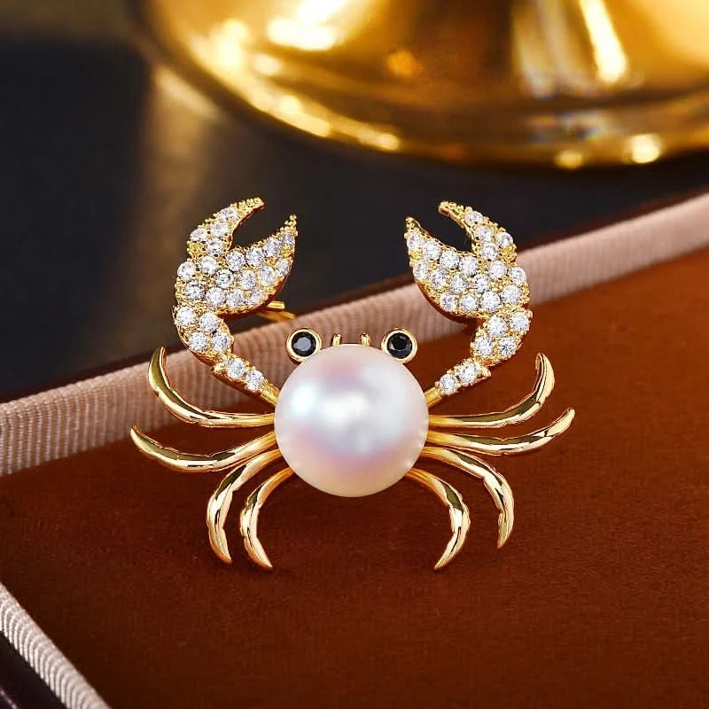Gold-tone pearl crab brooch with luminous pearl body and cubic zirconia claws styled on a warm background
