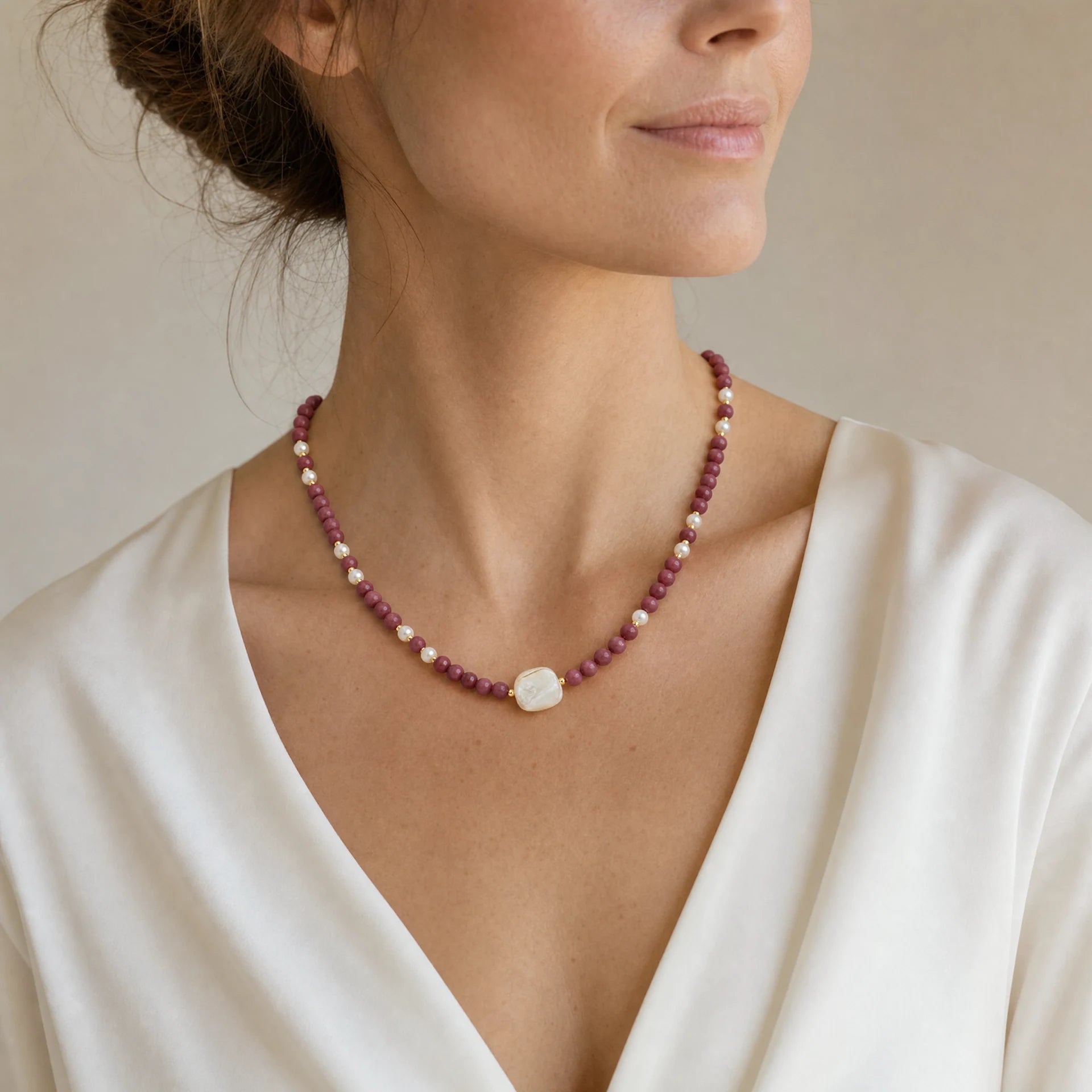 Rhodonite and mother-of-pearl beaded necklace with square centrepiece worn at a three quarter angle