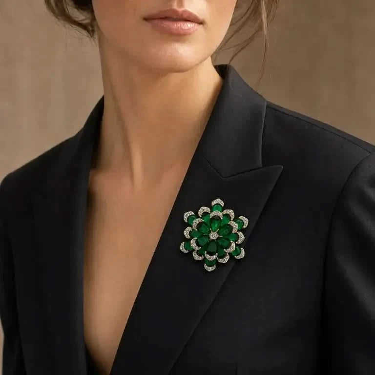 Emerald-green crystal flower brooch worn on a black blazer lapel