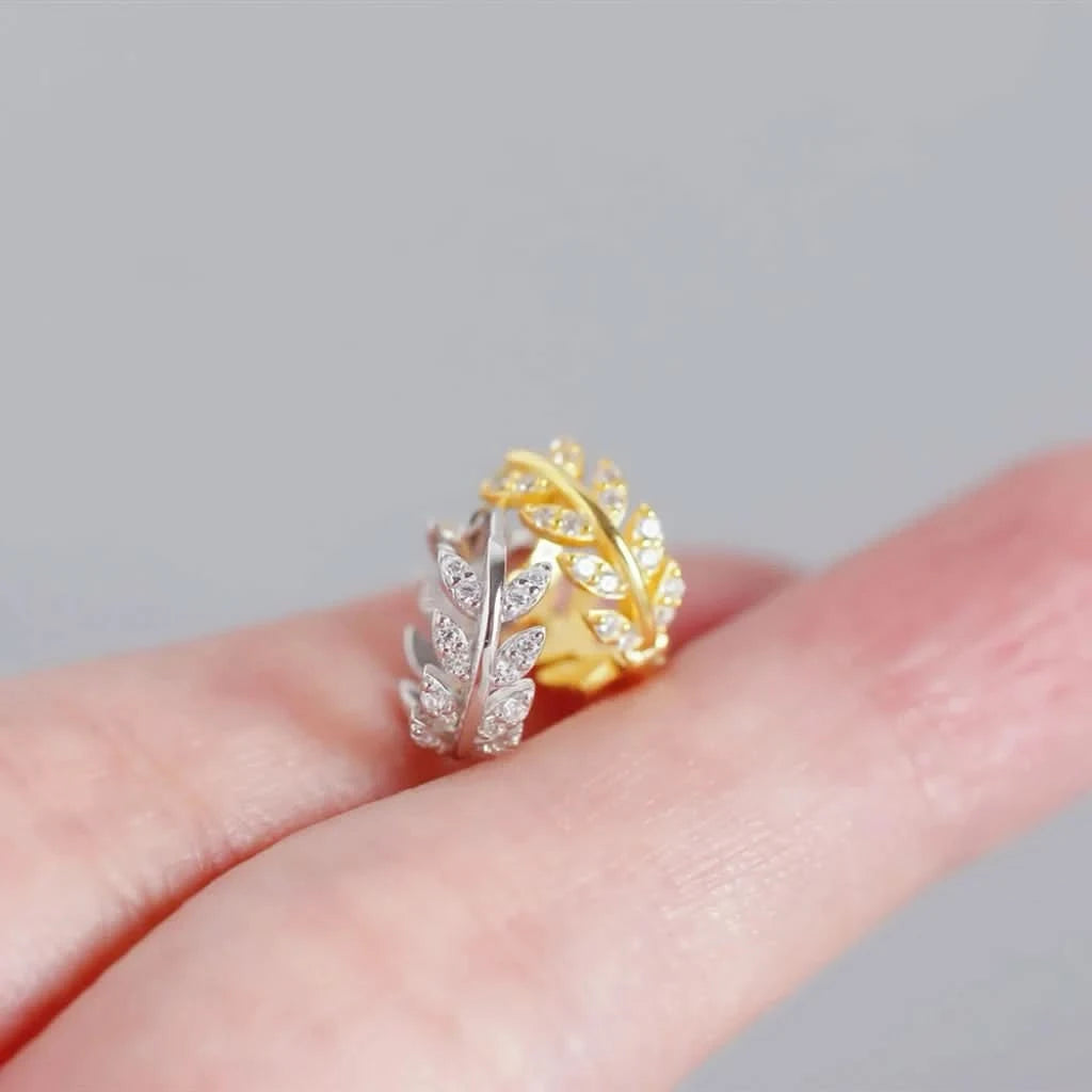 Gold and silver ring on a finger against a gray background
