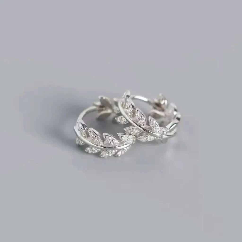 Pair of silver hoop earrings with small diamonds on a light gray background