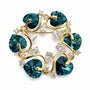 Gold tone teal heart crystal vine brooch on a white background