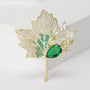 Green crystal maple leaf brooch with gold-tone stem and clear crystal branch details