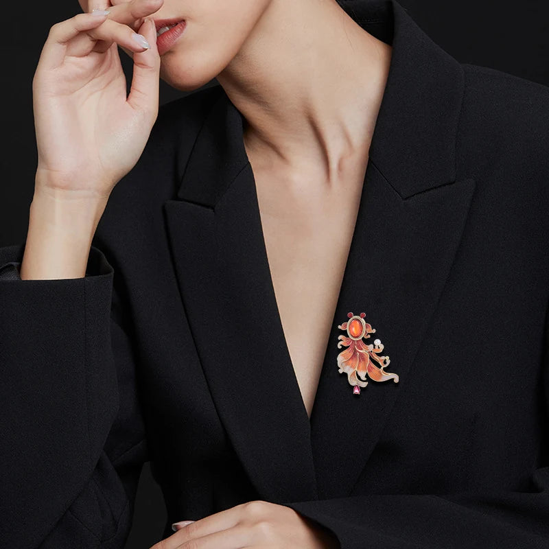 Orange enamel goldfish brooch worn on a black blazer lapel