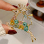 Multicolour crystal reindeer brooch held in hand, showing the sculptural antlers and leaping pose
