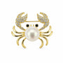 Gold-tone pearl crab brooch with cubic zirconia claws and black eyes on a white background