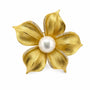 Brushed gold flower brooch with freshwater pearl centre and cubic zirconia details on a white background